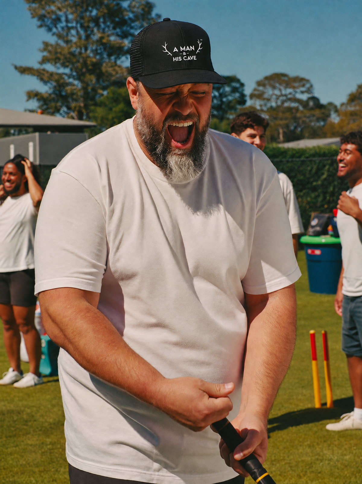 Bloke laughing at backyard cricket in the black AMAHC logo trucker cap