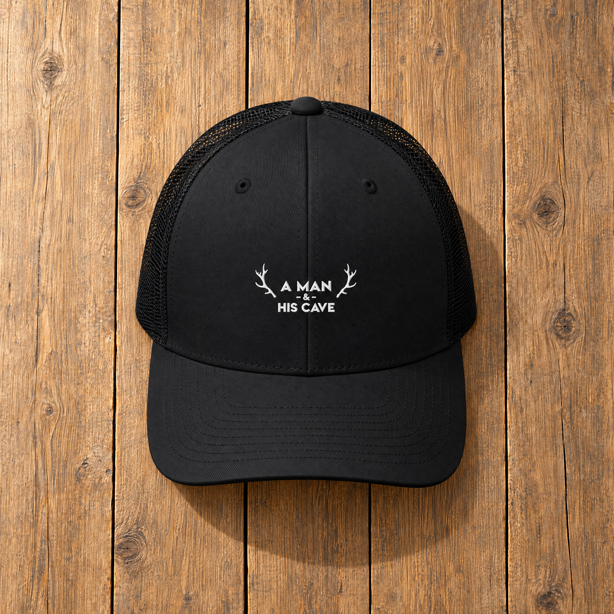 Black AMAHC logo trucker cap on timber