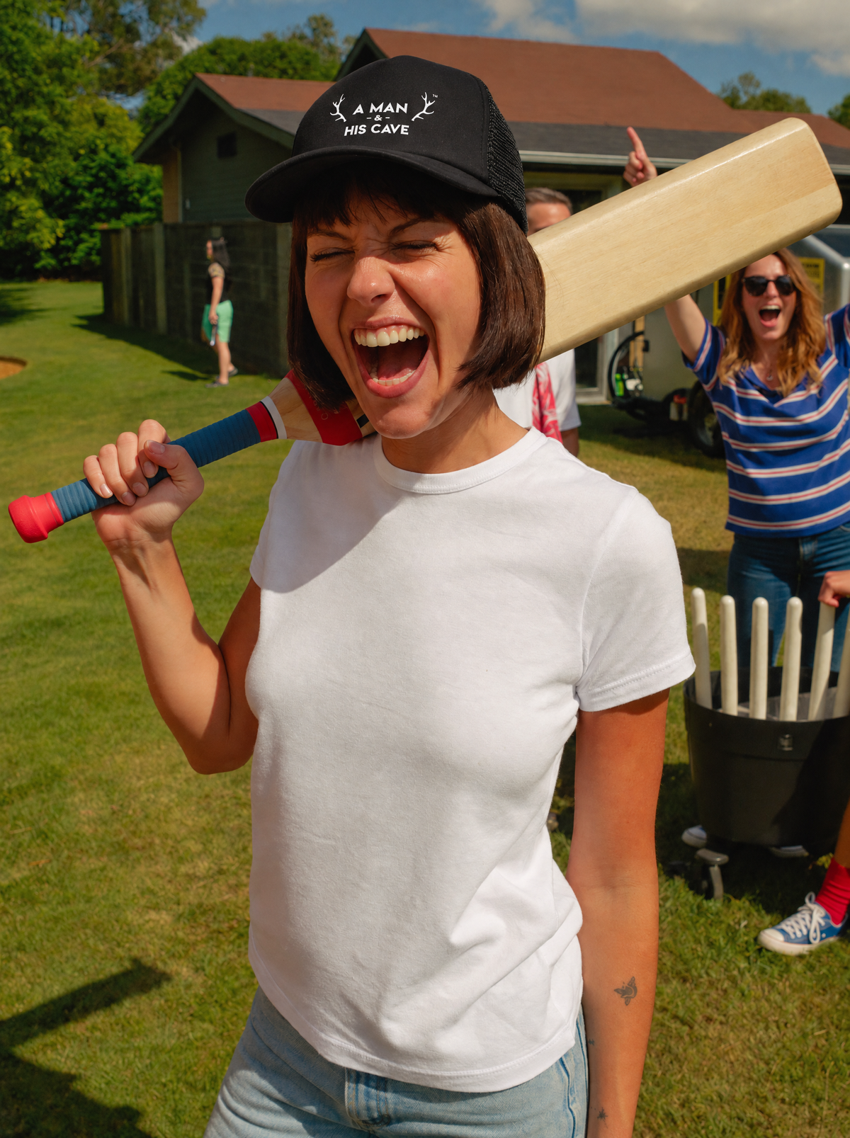 Woman laughing at backyard cricket in the black AMAHC logo trucker cap