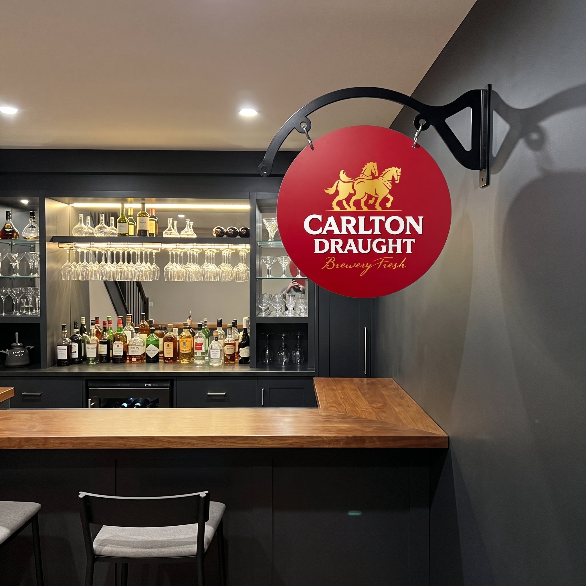 Carlton Draught round metal sign displayed in an indoor home bar
