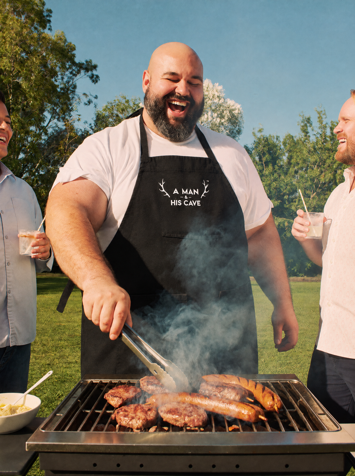 Big bloke on the barbecue tongs in the black AMAHC logo apron