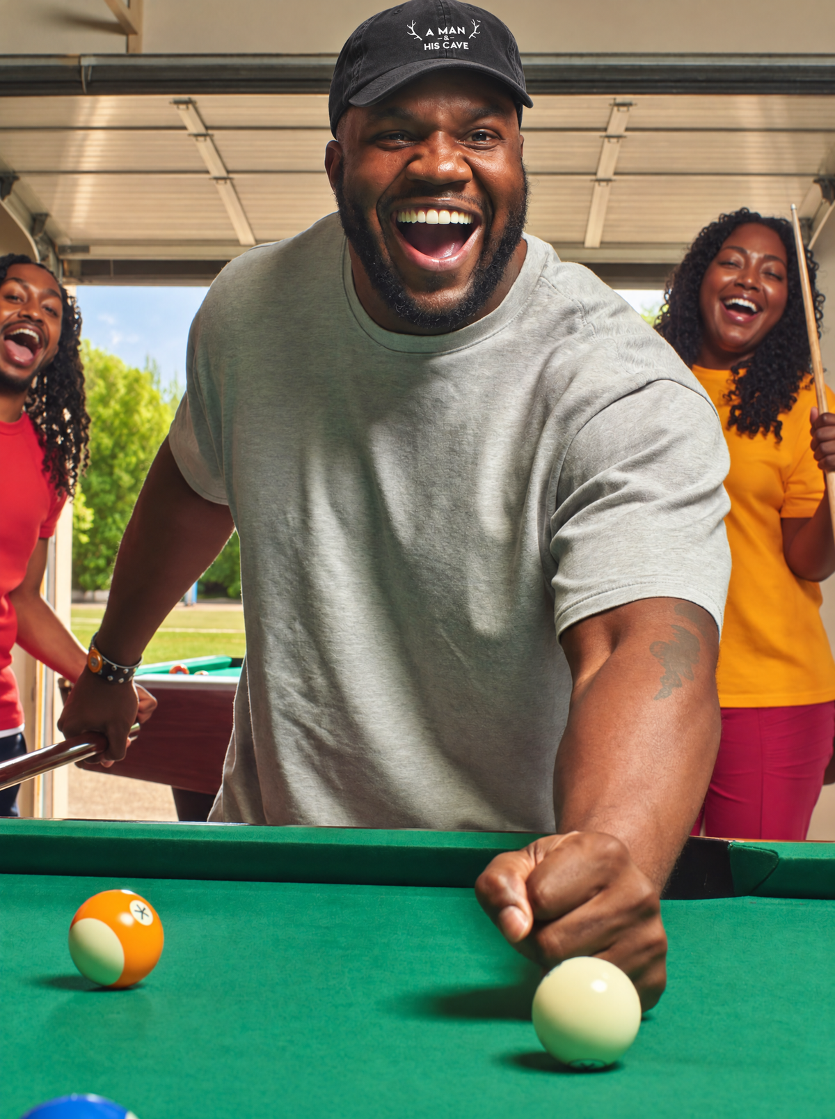 Big bloke celebrating a pool shot in the black AMAHC logo dad cap