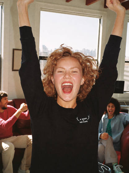 Woman cheering the footy in the black AMAHC logo crew sweatshirt