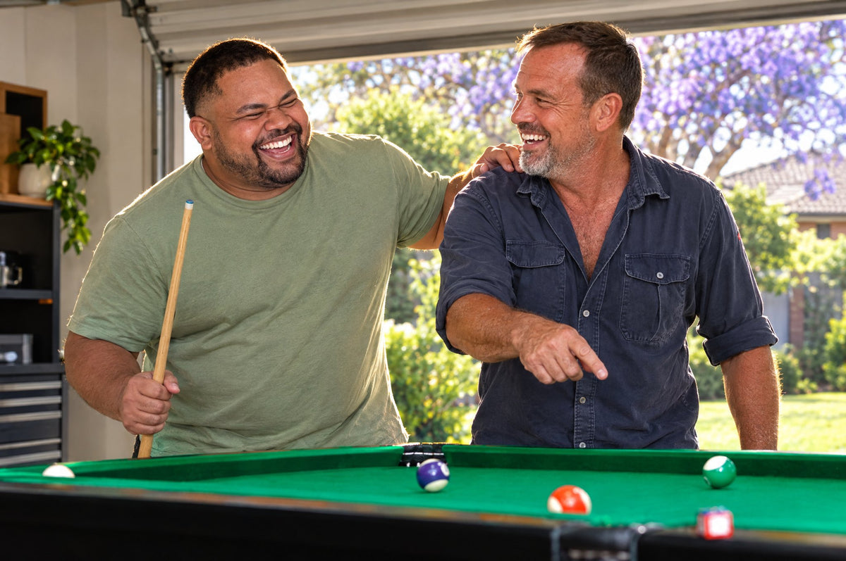 Two mates sharing a big laugh over a pool table in an open garage