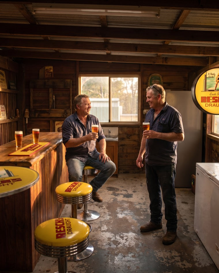 Mates in a shed bar with Resch's branded stools, table and LED sign